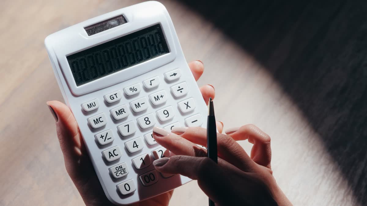Hands holding a calculator and pen while working out costs, representing auto injury coverage questions