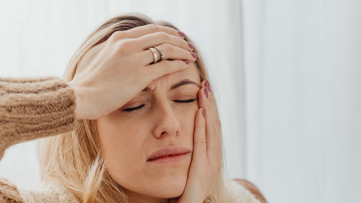 Woman with her hand on her forehead and cheek, showing the discomfort of a headache after a car accident