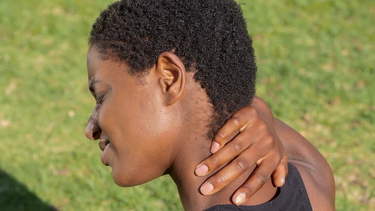 Woman holding the back of her neck, a common sign of whiplash after a car accident