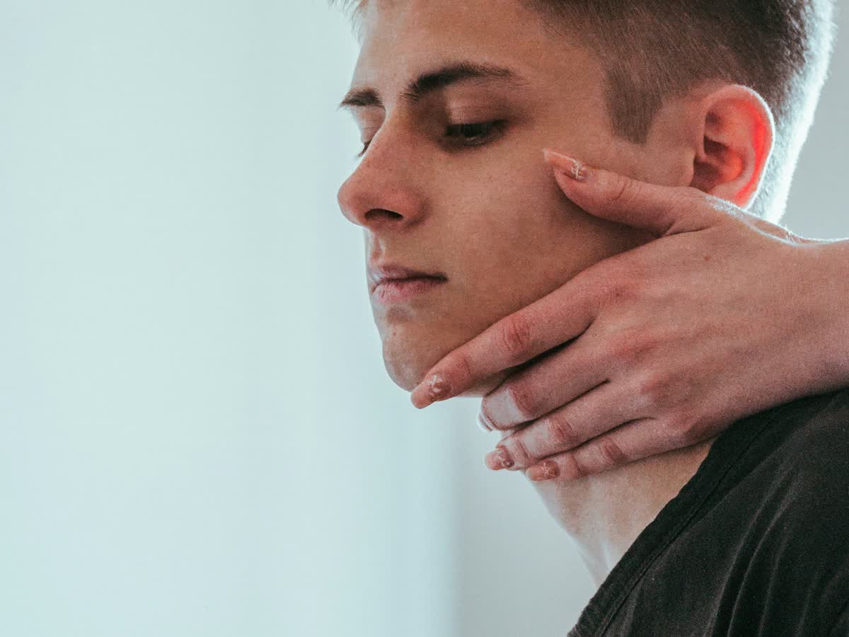 Practitioner's hands gently supporting a patient's neck