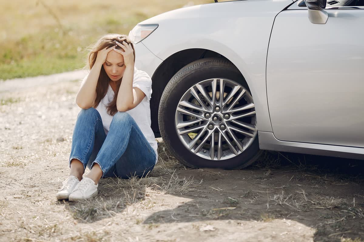 Woman sitting beside her car after an accident &mdash; auto injury care at Cedar Chiropractic in Milwaukie, Oregon