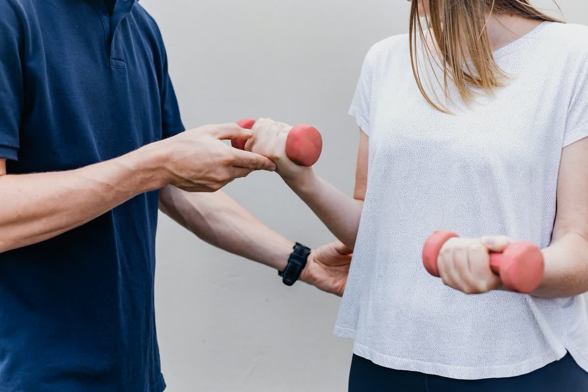 Patient doing a light dumbbell exercise while a clinician guides her form