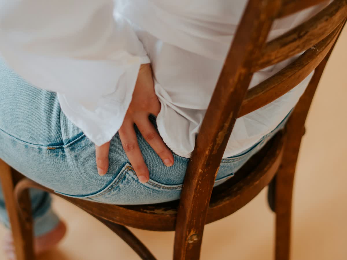 Seated woman pressing on her lower back and hip