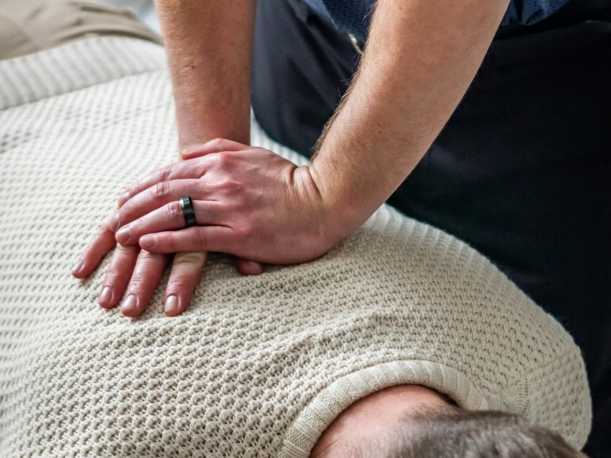 Chiropractor's hands giving a gentle upper-back adjustment