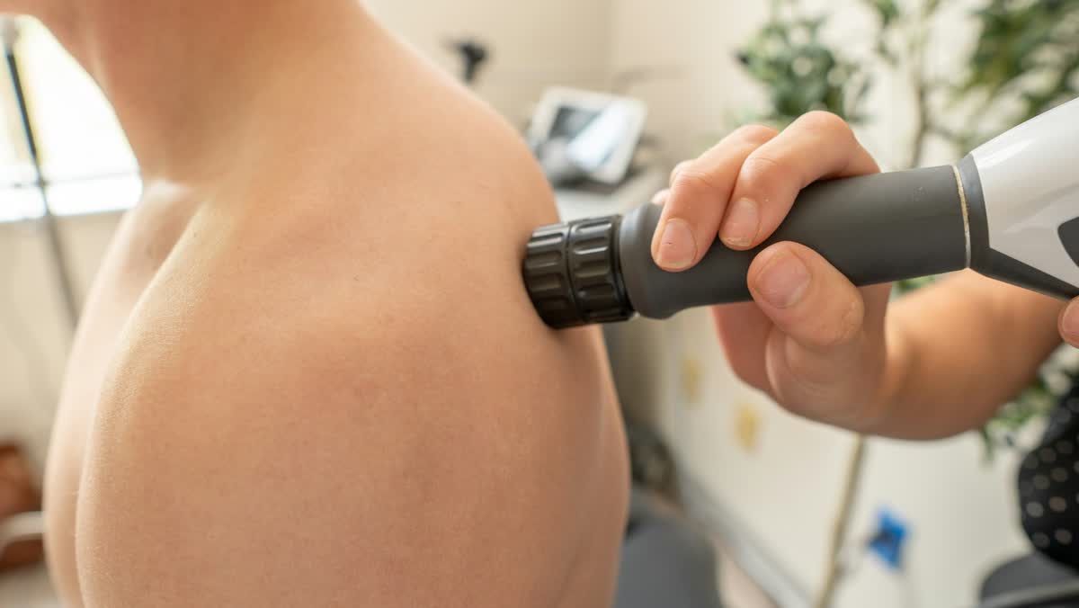 Therapy wand applied to the back of a patient's shoulder
